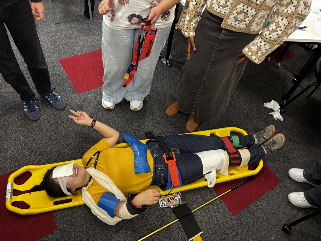 Student demonstrating full spinal immobilization with cervical collar and straps