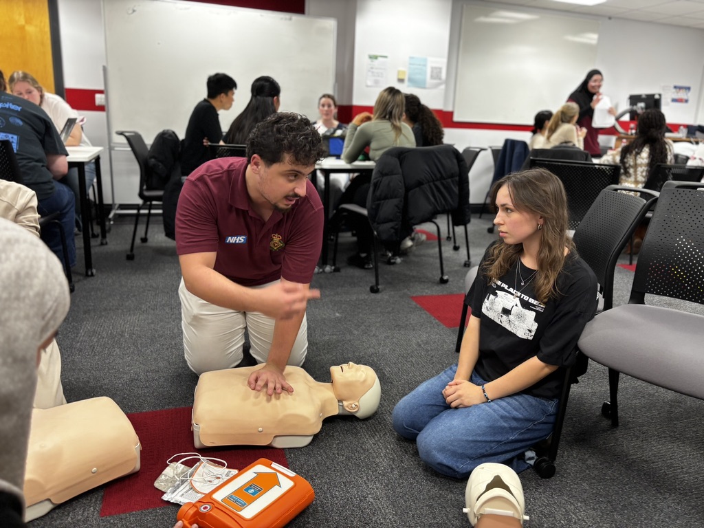 CFR member teaching CPR technique with AED defibrillator visible