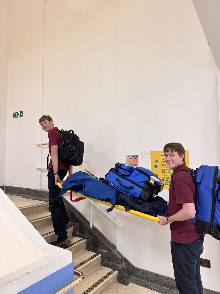 Cam and Rory carrying medical response bags and spinal board equipment